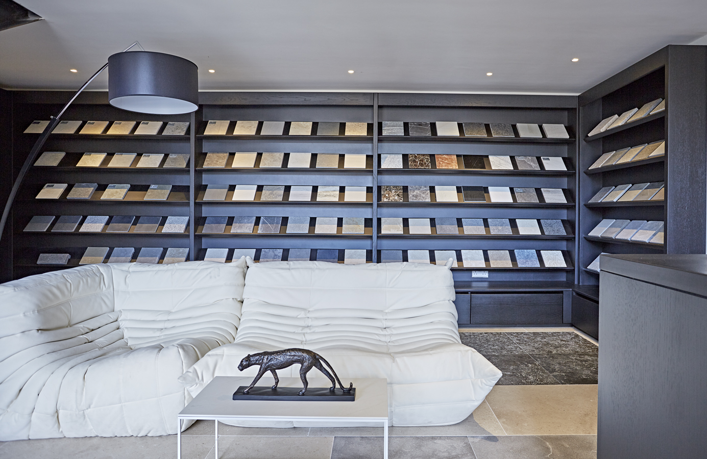 Stone sample display case sat on natural flagstone flooring with a Ligne Rosset Togo Settee infront of the display unit